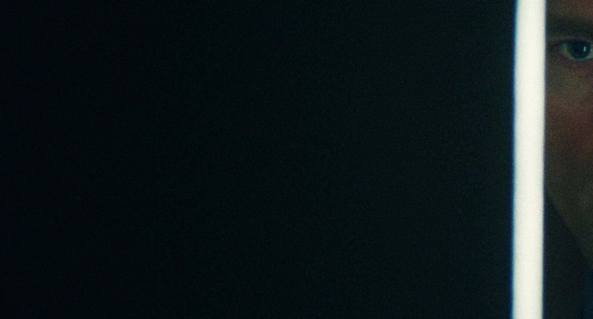 Wide night frame — darkness pressing against a lit doorway.